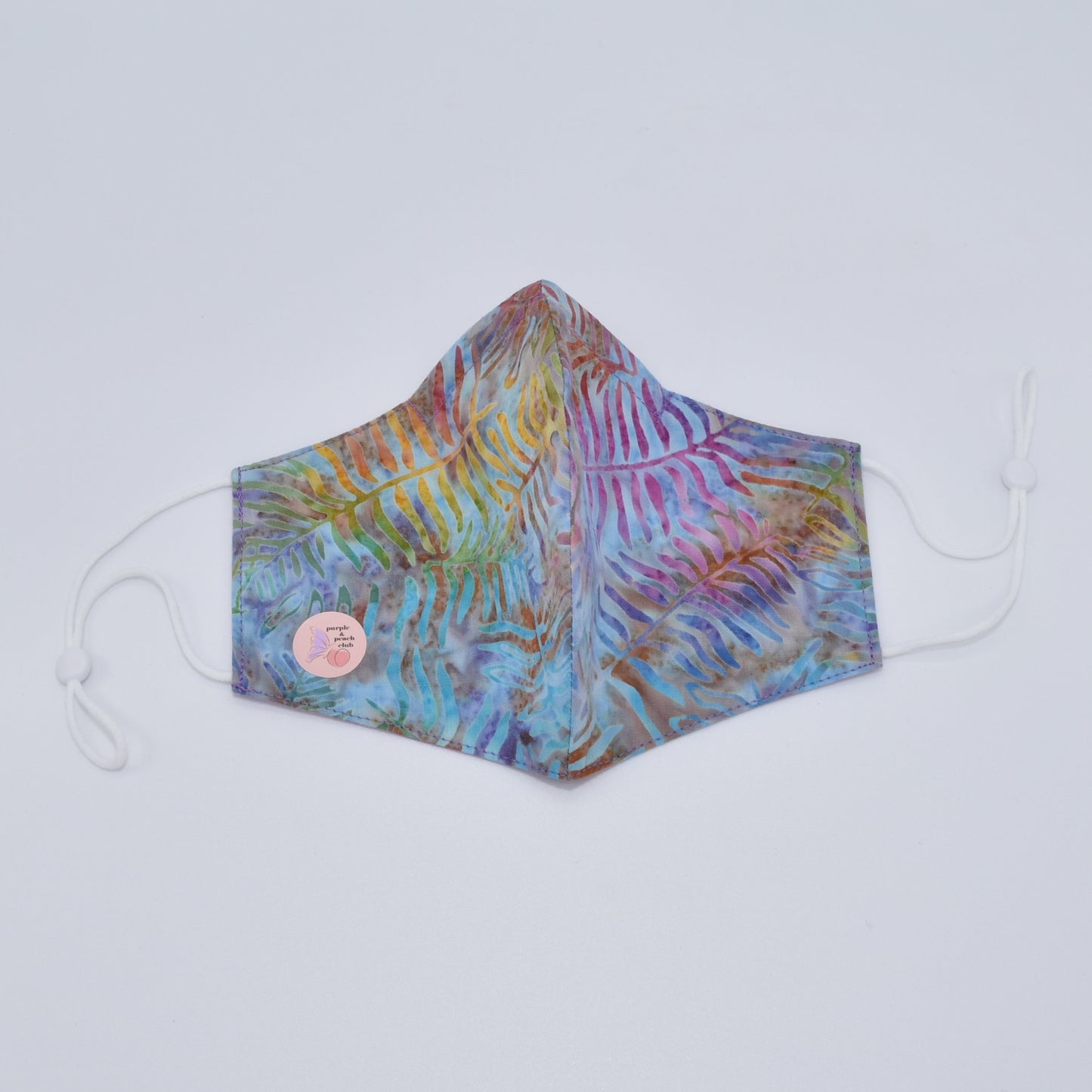 This leaf tie-dye print cotton mask is reversible and double-layered, built for comfort with an adjustable nose bridge and adjustable ear straps.