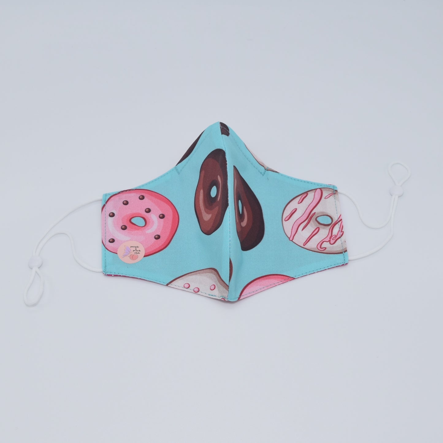 This colorful donut mask is perfect for any lover of sweets and fun prints. Made with one of our heavier-weight cotton novelty fabrics to provide a sturdier outer shell and the ultimate combination of both structure and comfort. Reversible and double-layered. Built with an adjustable nose bridge and adjustable ear straps.