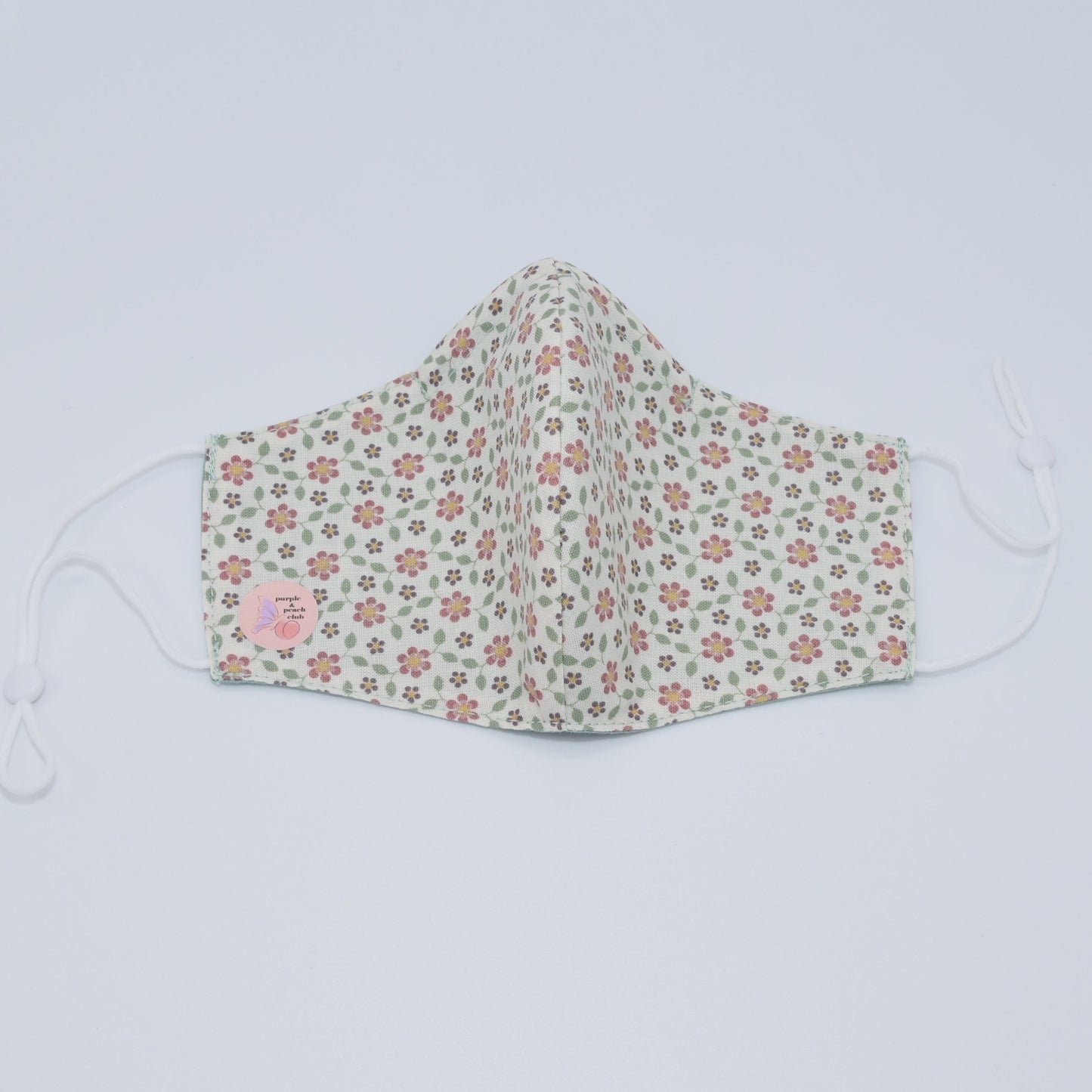 The simple flower details against the soft off-white cotton fabric make this mask a graceful accessory.  One of our lighter and softer designs. Reversible and double-layered. Built for comfort with an adjustable nose bridge and adjustable ear straps. 