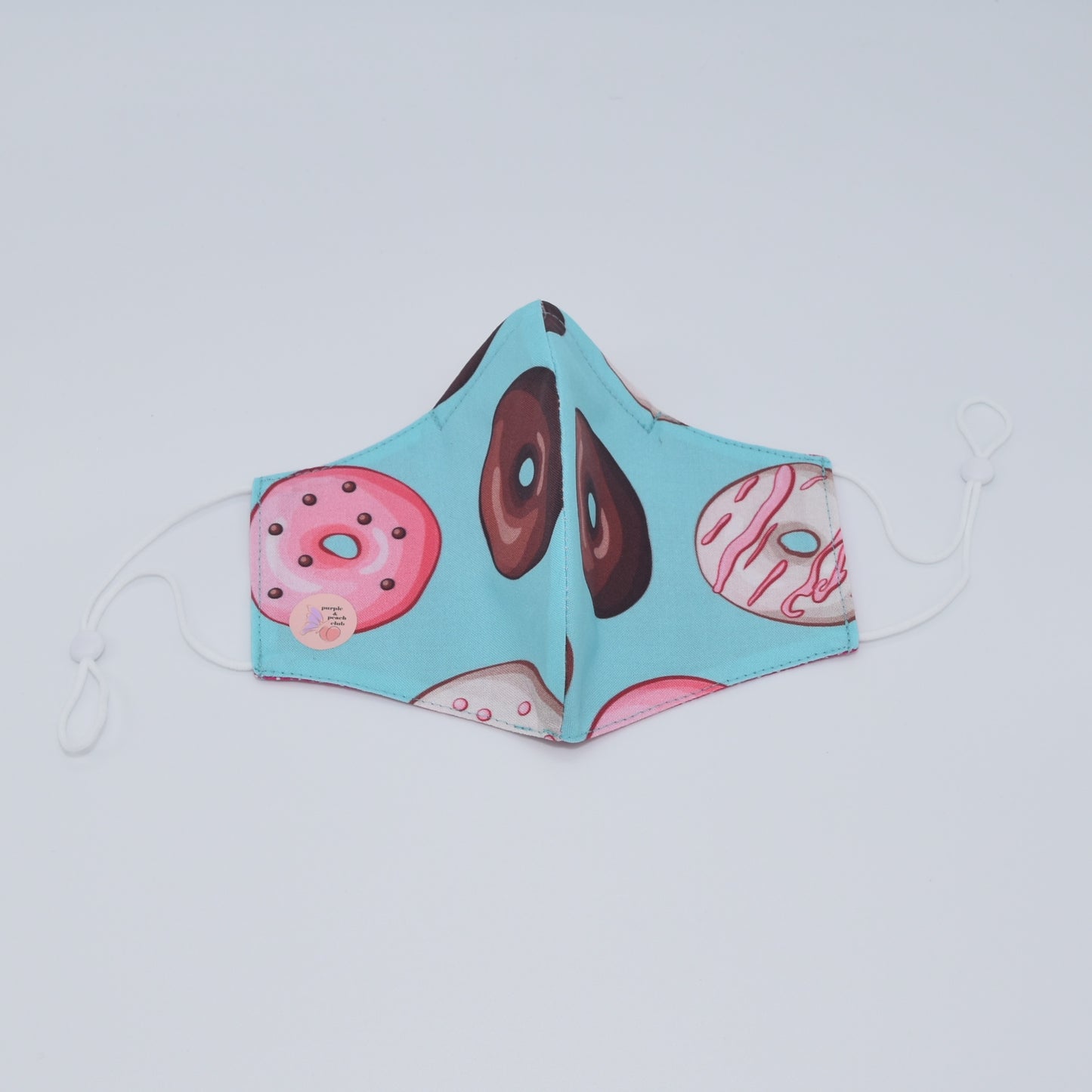This colorful donut mask is perfect for any lover of sweets and fun prints. Made with one of our heavier-weight cotton novelty fabrics to provide a sturdier outer shell and the ultimate combination of both structure and comfort. Reversible and double-layered. Built with an adjustable nose bridge and adjustable ear straps. 